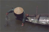 A person wearing a broad hat beside a boat